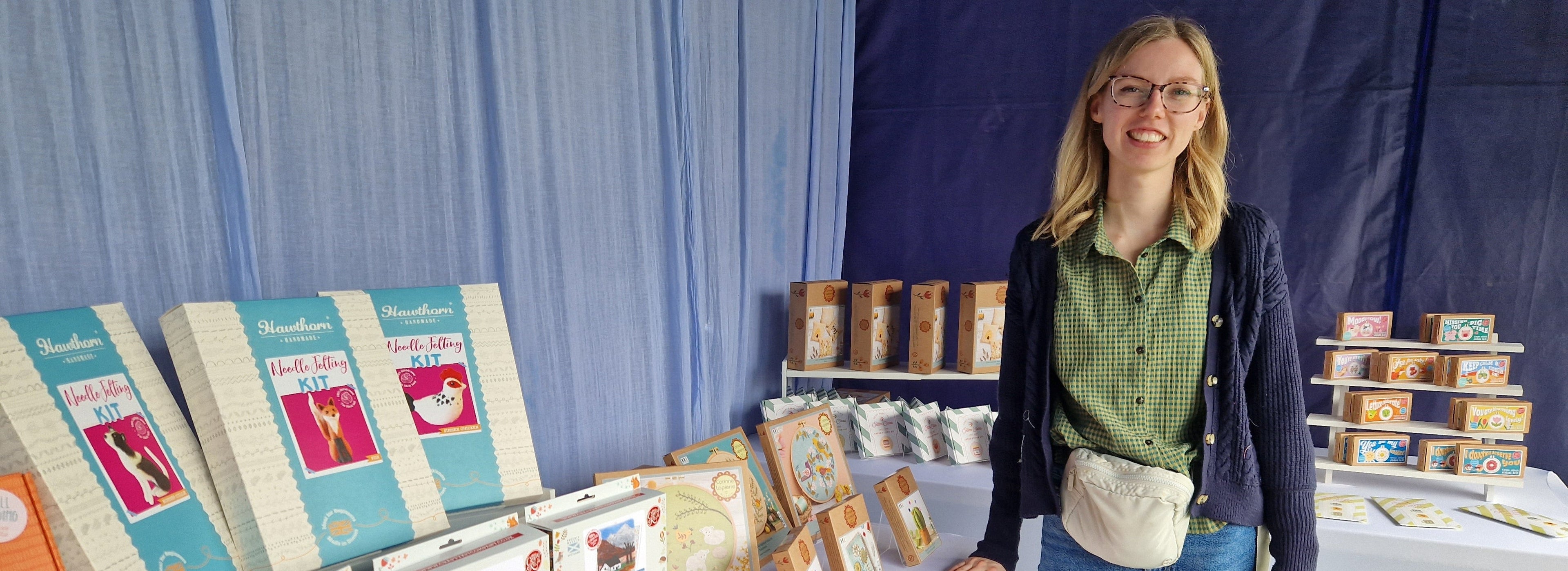 Woman standing next to a display of craft kits at the Knit Stitch Chill stall at the Clogher Valley Show 2025