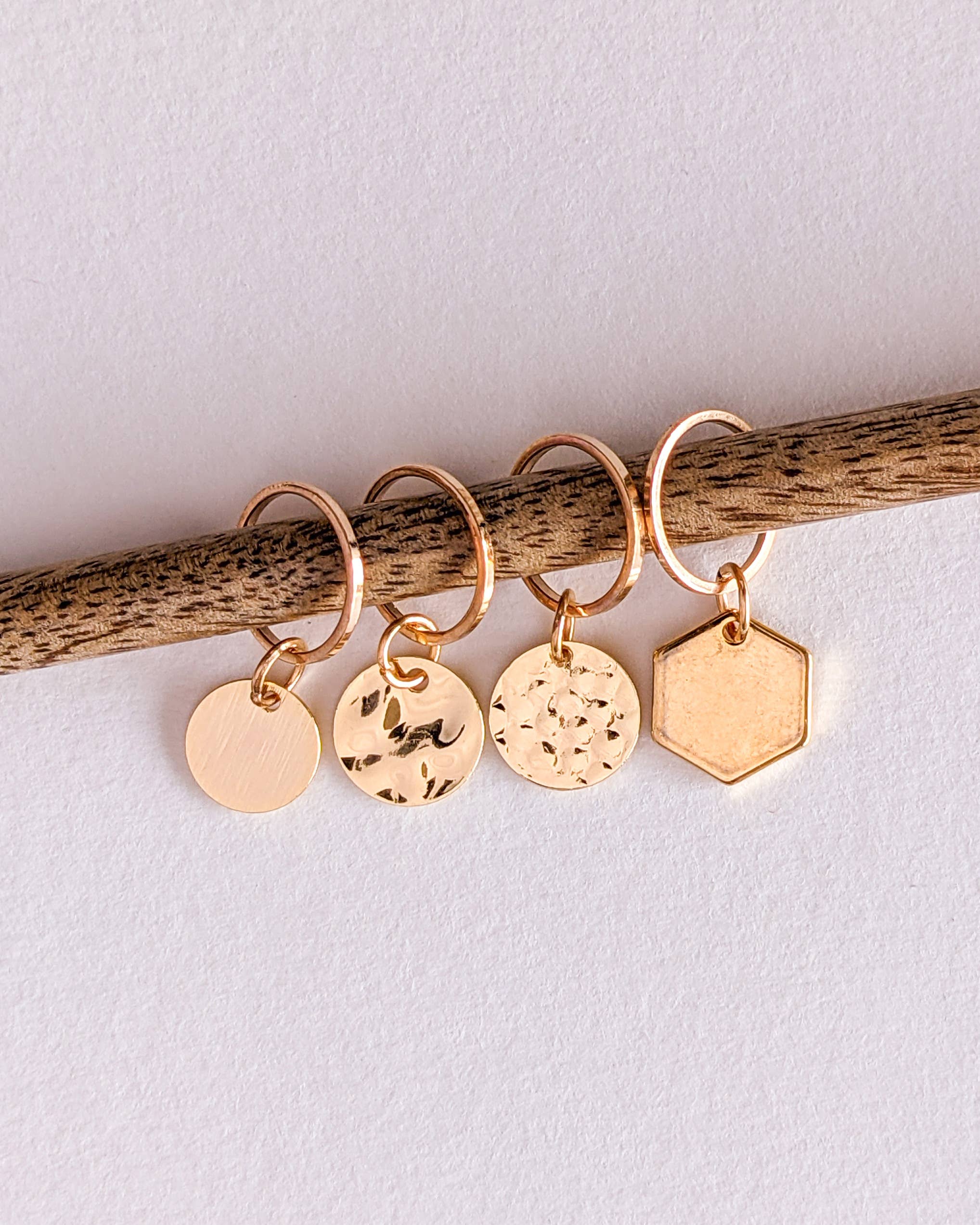 Set of four gold-plated ring stitch markers on a knitting needle with a white background